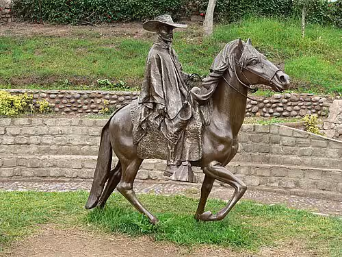 Caballos de paso en un sendero del Valle Sagrado, con montañas al fondo.